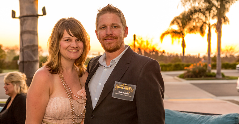 Nick Batliner and his wife stand on the patio with the sunset in the background
